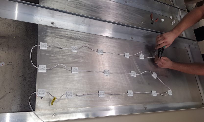 Installing LED channel units in a silver-colored backlit sign cabinet